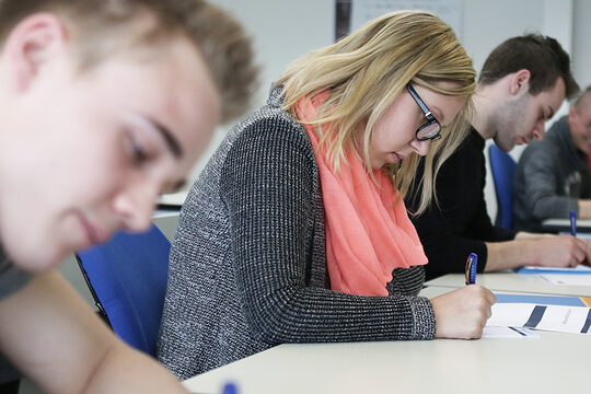 Junge Handwerkerinnen und Handwerker bei der schriftlichen Meisterprüfung