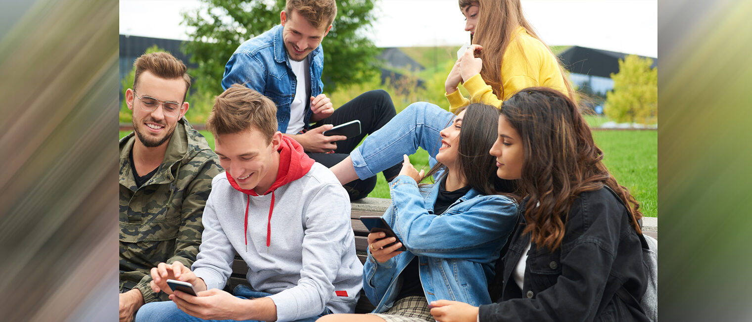 Jugendliche Gruppe sitzt zusammen und schaut auf Smartphones