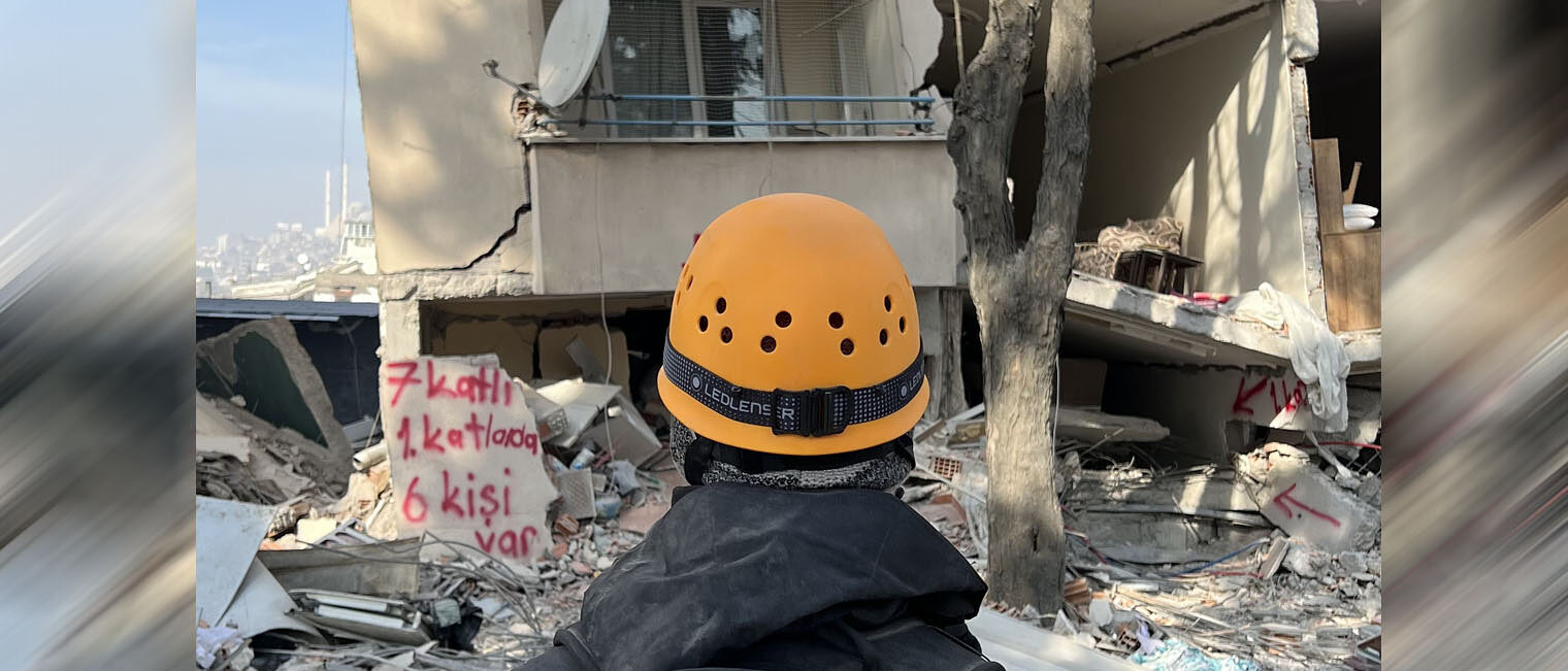 Deathcare Embalmingteam Germany e. V. Mann mit Helm steht vor der Ruine eines Hochhauses