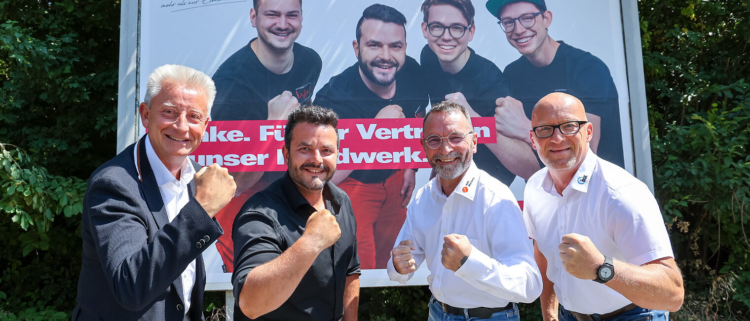 Gruppe posiert vor großem Werbeplakat