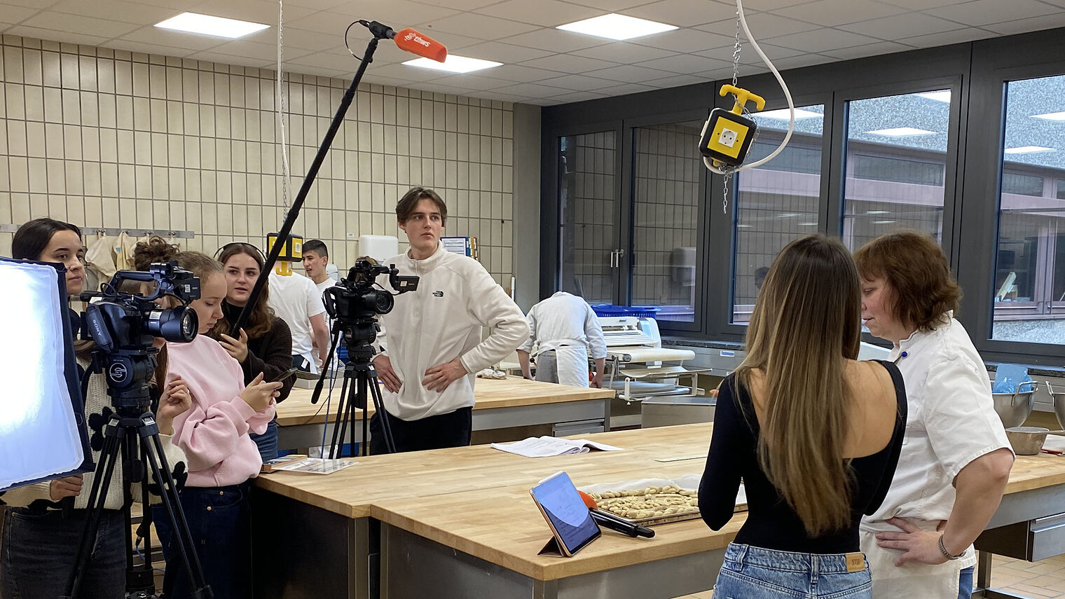 Gruppe von Studierenden mit Kameras und Mikrofon in der Backstube des Bildungszentrum bei einem Videodreh