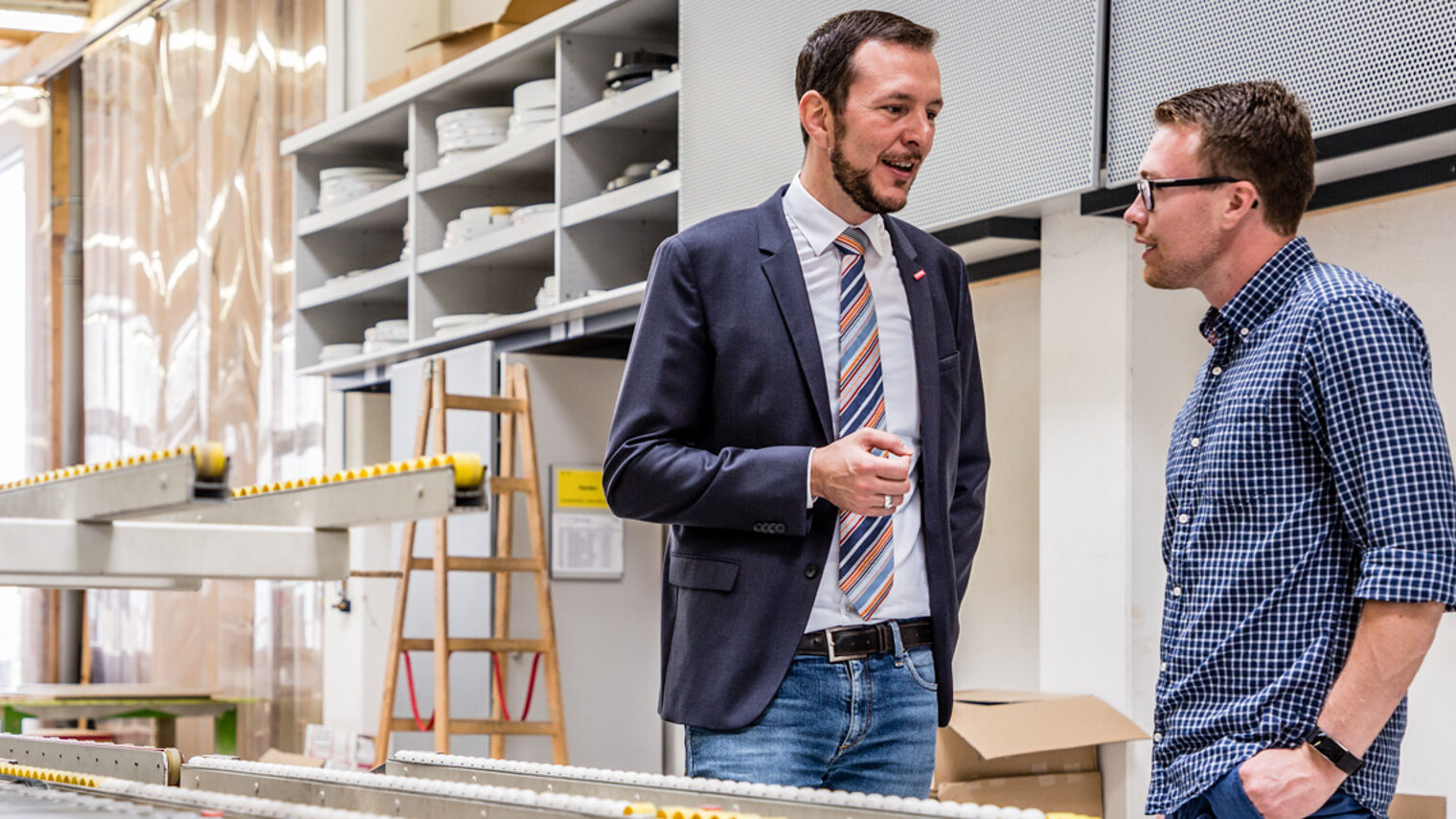 Berater und Betriebsinhaber im Gespräch an einer CNC-Maschine 