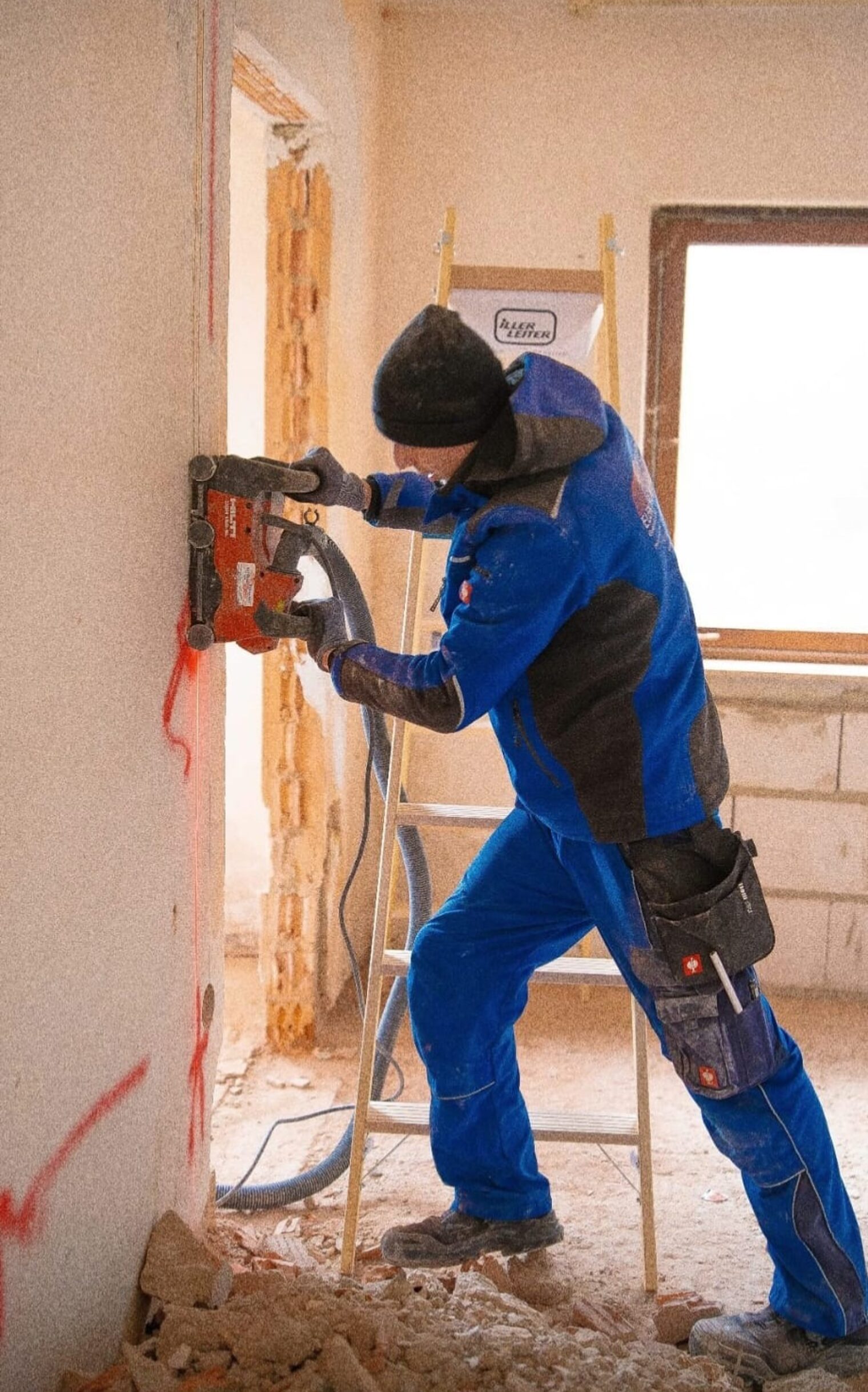 Elektroniker auf Baustelle, mach mit Maschine Schlitze in die Wand