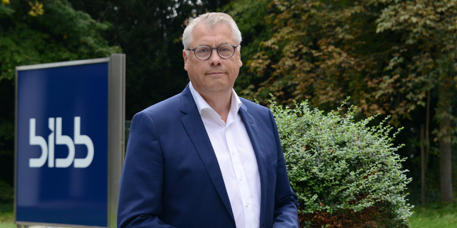 Porträtfoto draußen, im Hintergrund Stele mit Schriftzug "BIBB"
