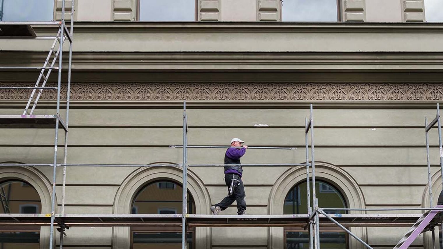 Totale von Gerüst an Gebäude mit einem darauf laufenden Gerüstbauer