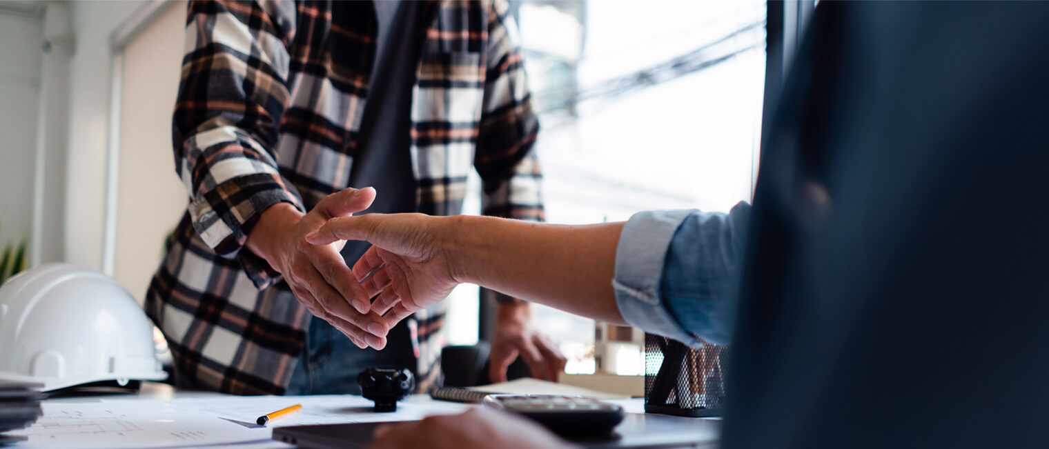 Handschlag zweier Männer über einen Schreibtisch hinweg