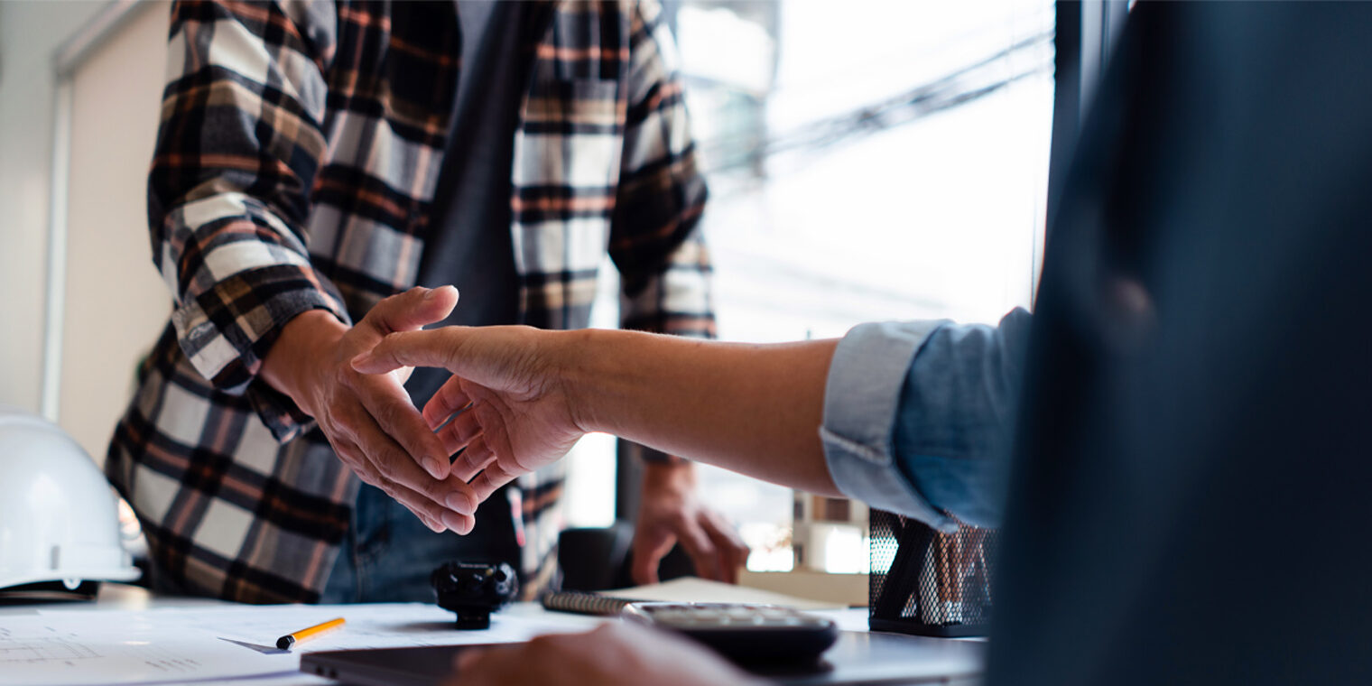 Handschlag zweier Männer über einen Schreibtisch hinweg