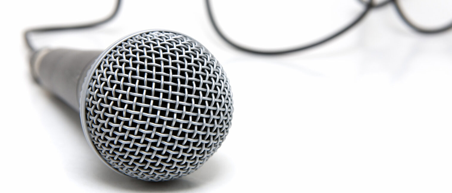 Nahaufnahme eines Mikrofons auf weißem Untergrund, dahinter das Kabel
